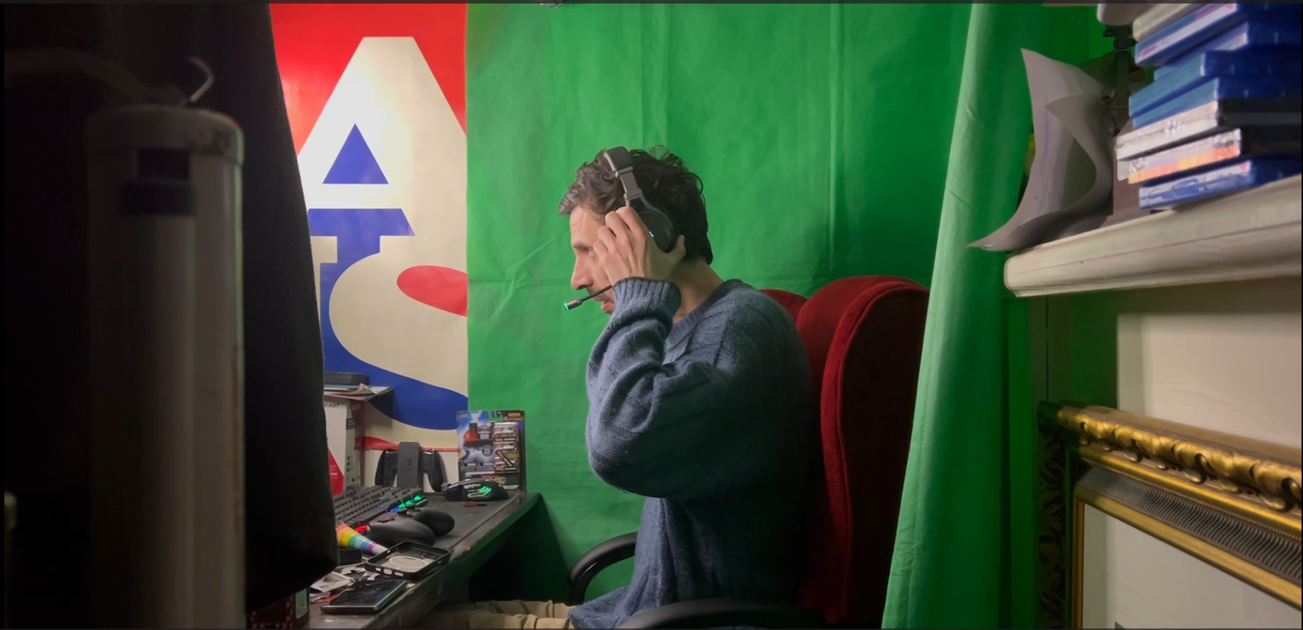 GreenUnderScoreHat putting on his headset in front of a green screen